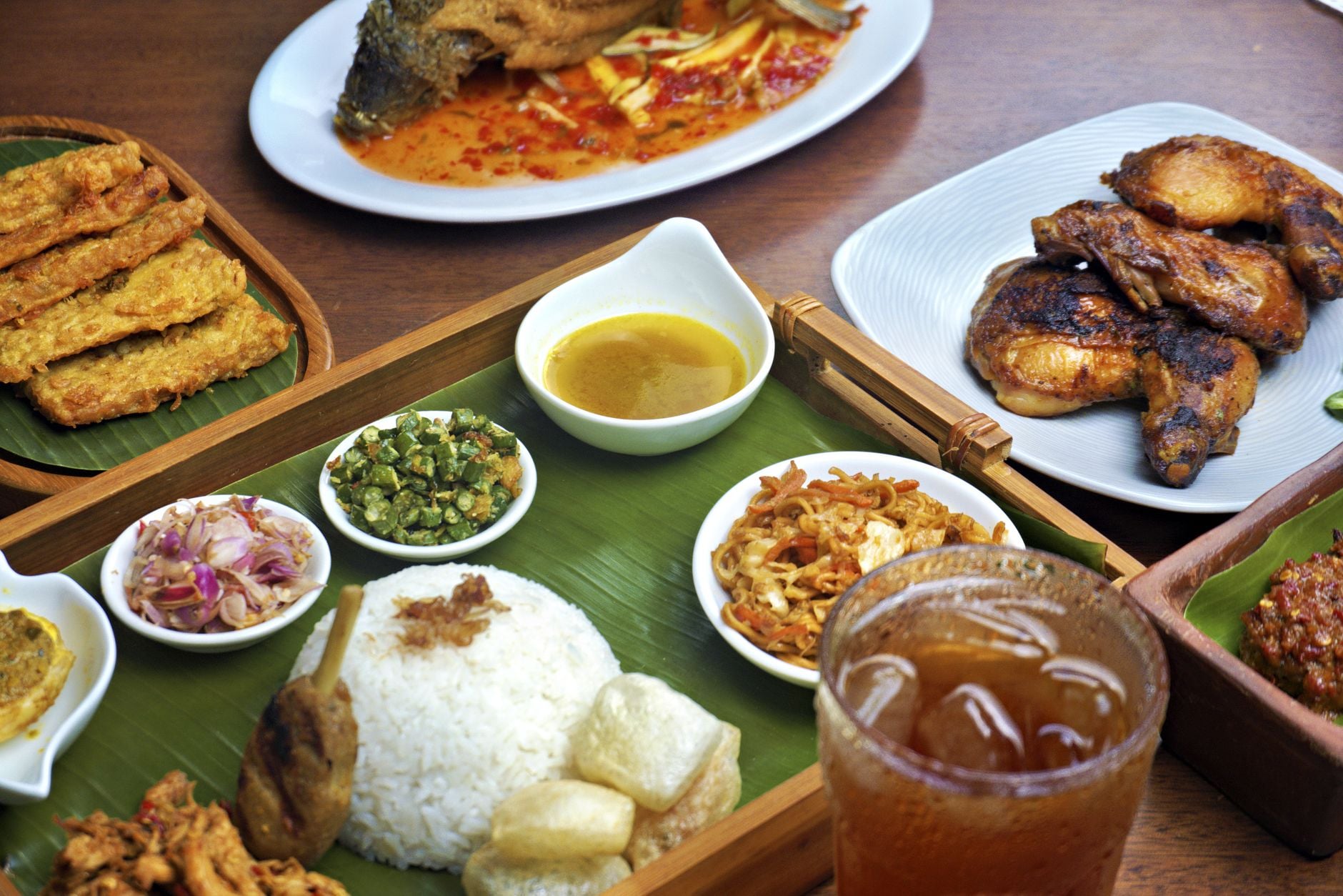 Traditional Indonesian Sundanese meal spread with rice on banana leaf, grilled chicken, fried tempeh, sambal and side dishes