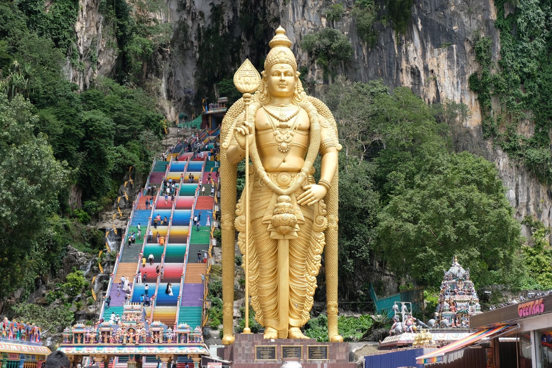 Den gyldne statue af Lord Murugan, der står foran de regnbuefarvede trin, der fører op til Batu-hulerne, Malaysia