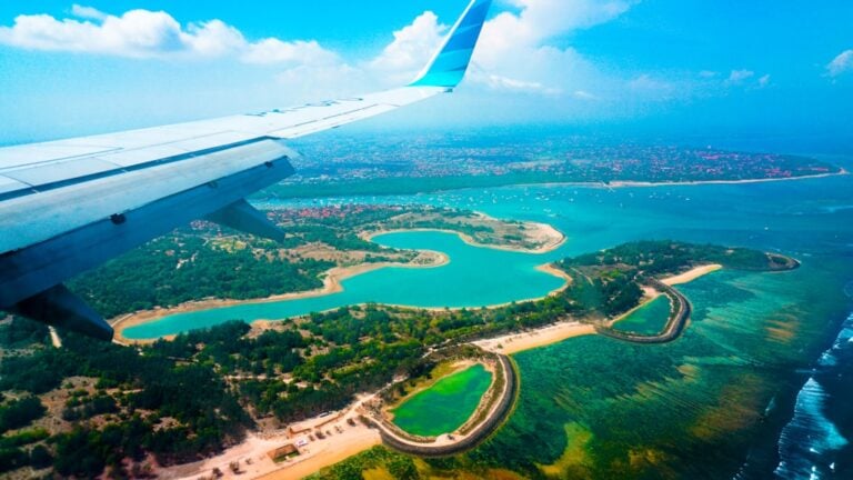 Aerial view of Bali's coastline and lagoons seen from a plane window approaching Ngurah Rai International Airport