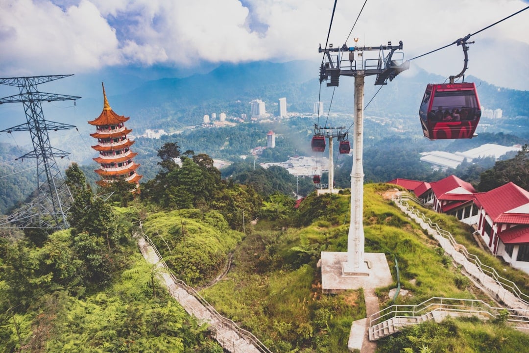 Awana SkyWay cable car ascending through the mist toward Genting Highlands resort with a pagoda temple visible below