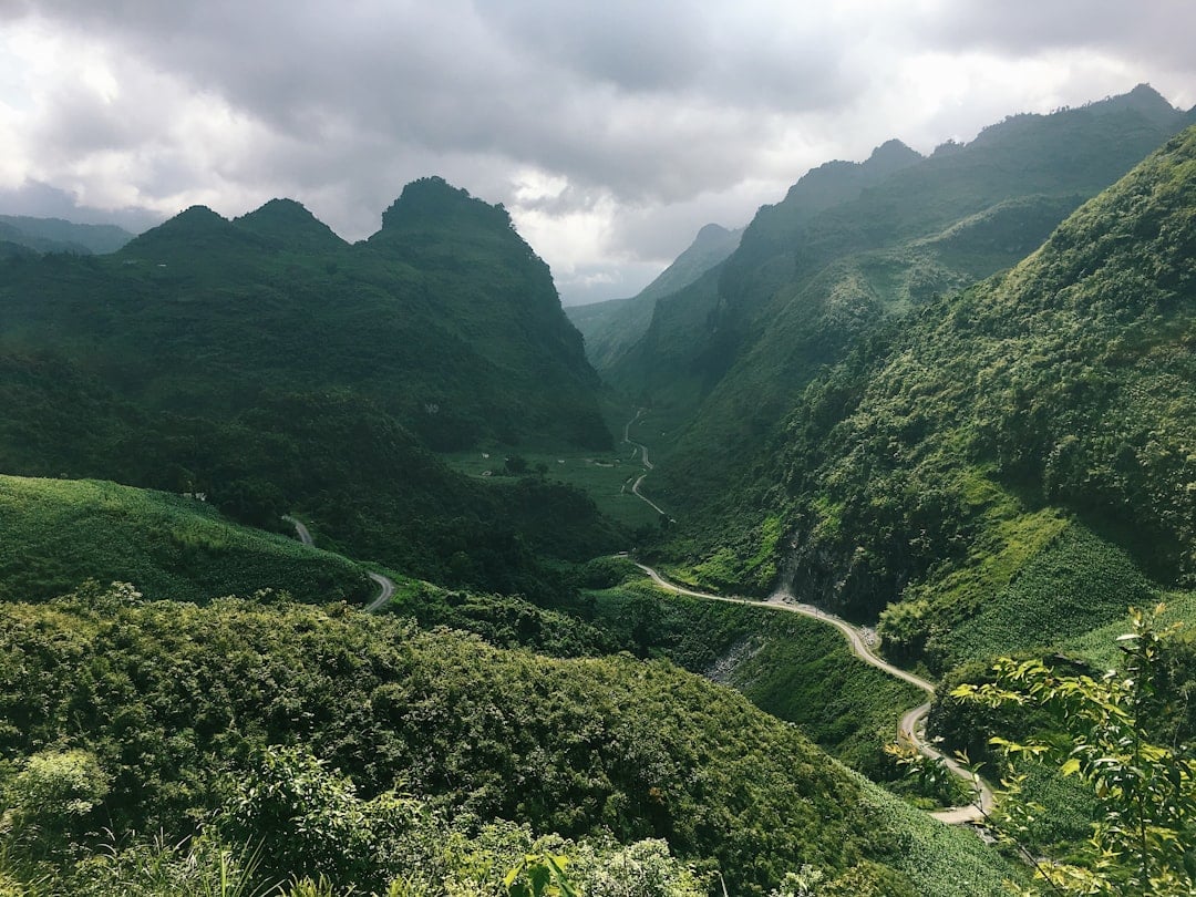 ถนนบนภูเขาคดเคี้ยวตัดผ่านหุบเขาหินปูนสีเขียวชอุ่มอันงดงามทางตอนเหนือ Vietnam ใกล้ชายแดนจีน