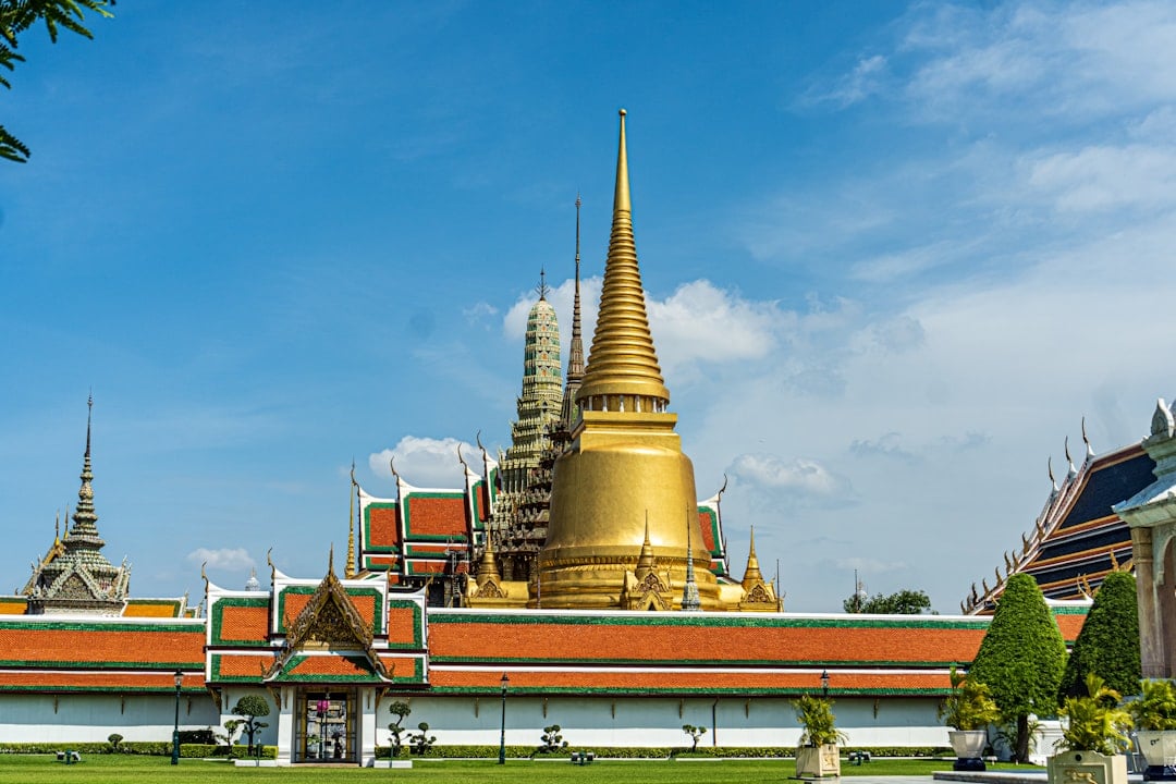 The Grand Palace Bangkok with golden chedi and ornate Thai temple architecture under blue sky