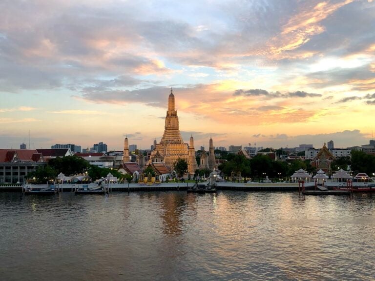 Wat Arun temple at sunset reflected on the Chao Phraya River, Bangkok, Thailand