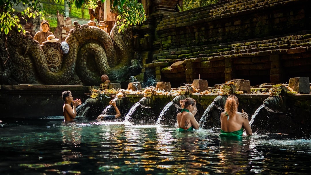 Visitors bathing at the holy spring spouts of Tirta Empul temple in Bali, participating in the traditional Balinese Hindu purification ritual