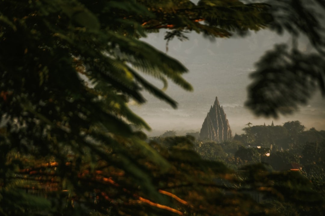 Prambanan Hindu temple central spire seen through lush tropical foliage at dusk, Yogyakarta, Java, Indonesia
