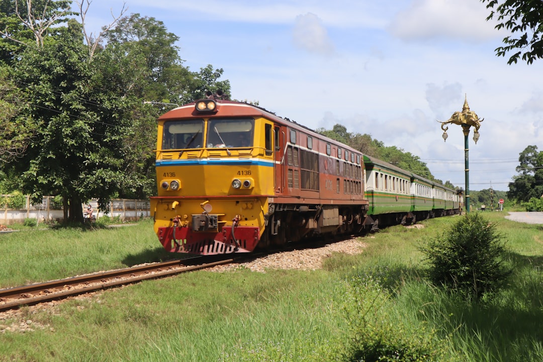 Kereta api diesel Thailand melintasi pedesaan hijau yang subur. Thailand