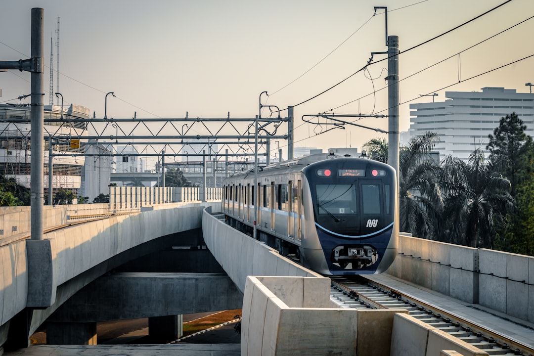 Jakarta MRT train arriving at Blok M elevated station with the city skyline visible in the background, Indonesia