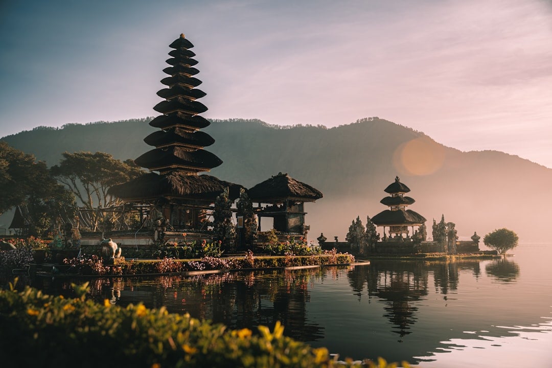 Ulun Danu Beratan temple reflected in misty lake waters with mountain backdrop in Bali, Indonesia