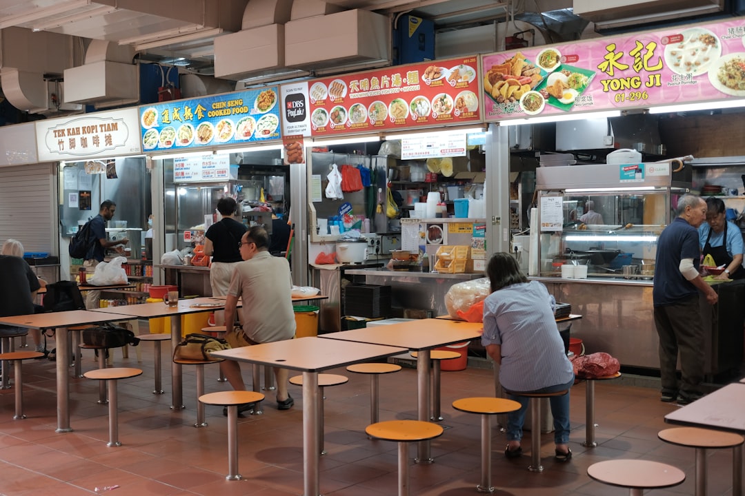 Singapore hawker centre with food stalls and locals eating at tables and stools