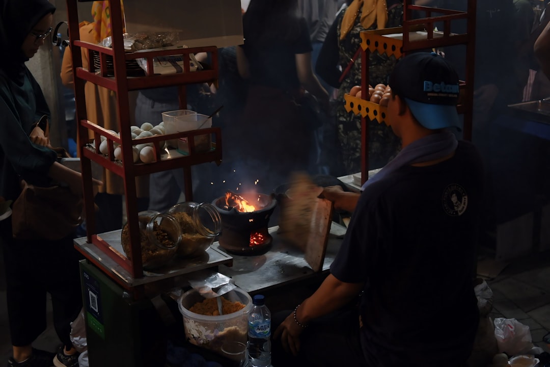 A Jakarta street food vendor preparing kerak telor, the traditional Betawi egg and rice pancake cooked over hot coals, Jakarta Indonesia
