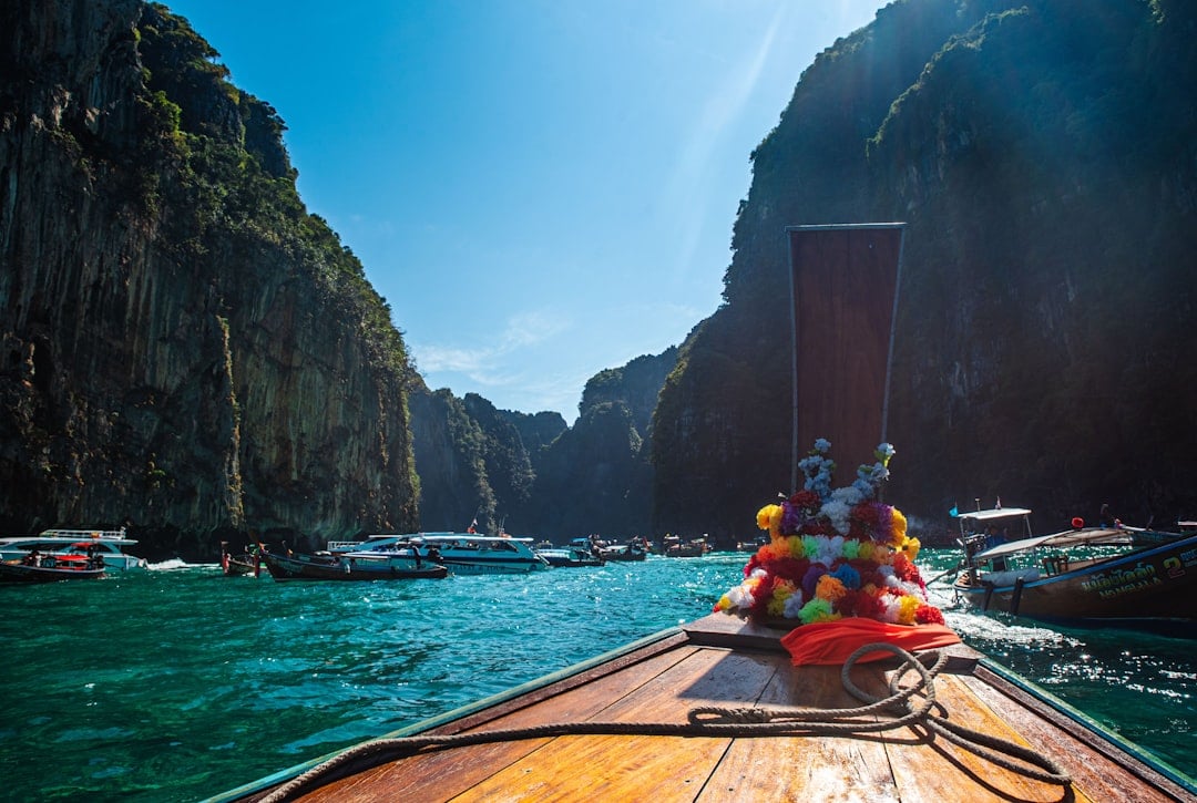 View from the bow of a longtail boat approaching Maya Bay, Phi Phi Island, with turquoise water and limestone cliffs on either side