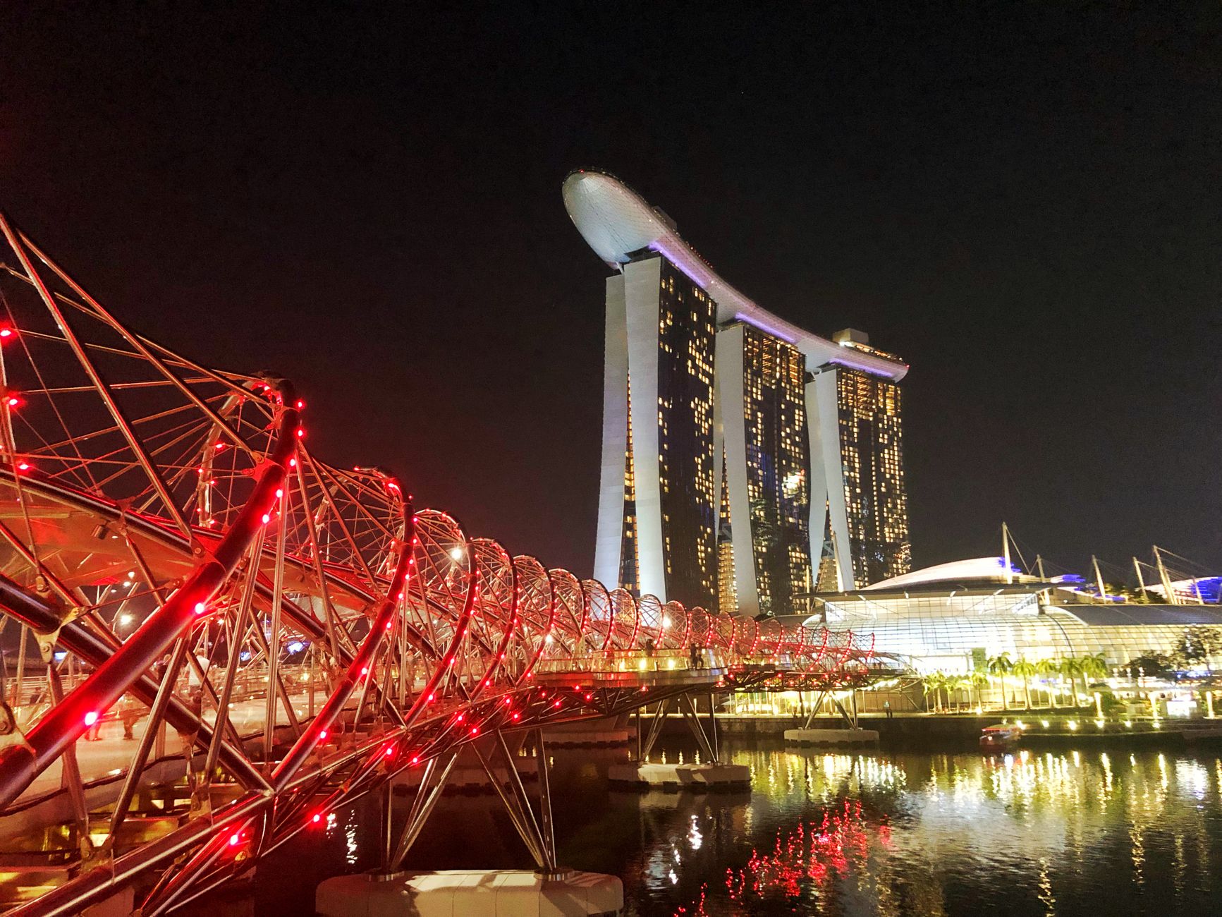 Helix Bridge illuminated at night with Marina Bay Sands glowing behind it, Singapore