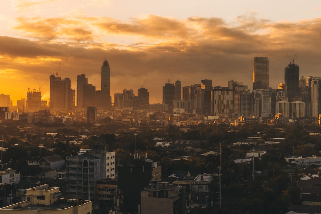 Manila Philippines city skyline at golden hour with skyscrapers and dramatic sunset sky