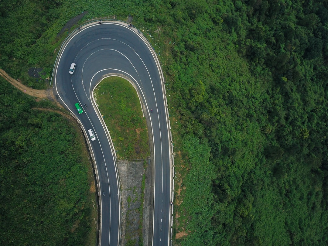Aerial view of tight hairpin switchback road through dense green mountain forest on the Hai Van Pass, Vietnam
