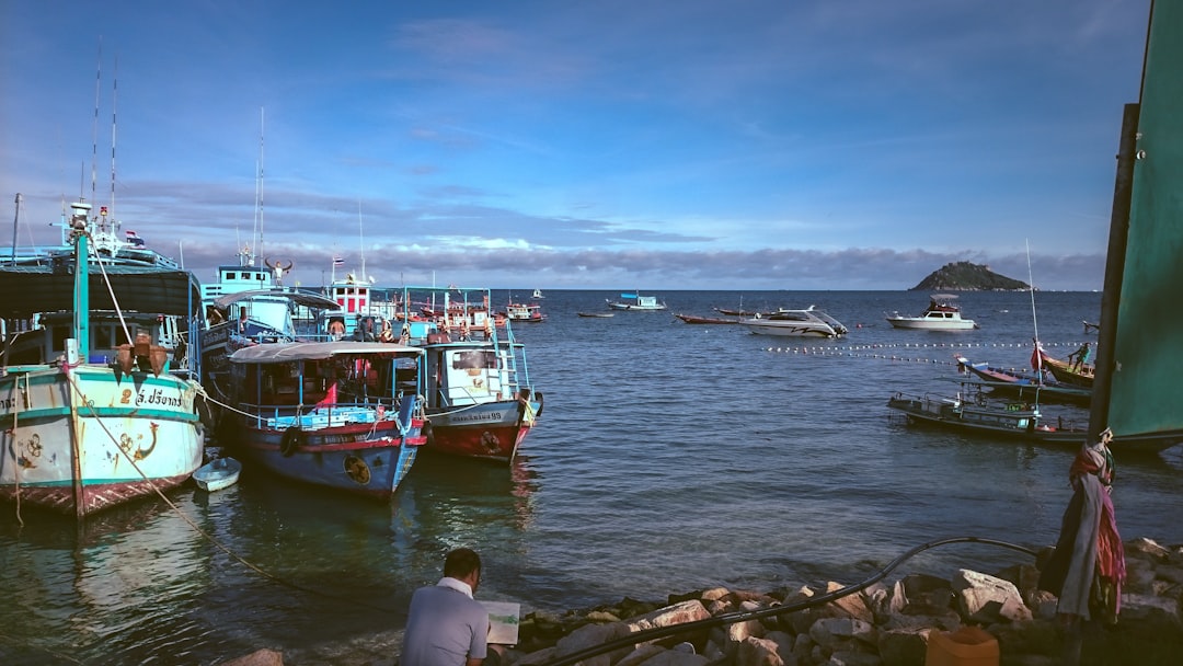 Longtail boats and fishing vessels moored at a Thai island pier in the Gulf of Thailand on a calm morning