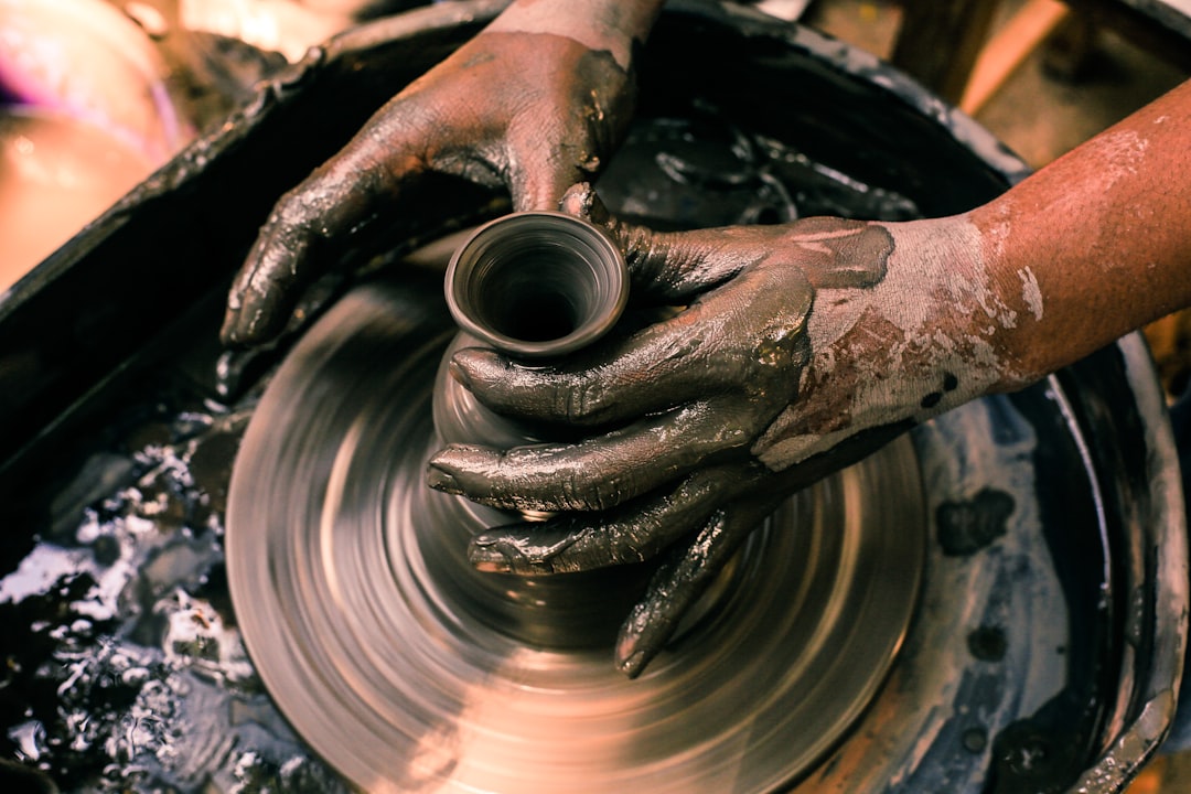Potter's hands shaping clay on a wheel, traditional burnay pottery craft similar to Vigan's Pagburnayan district