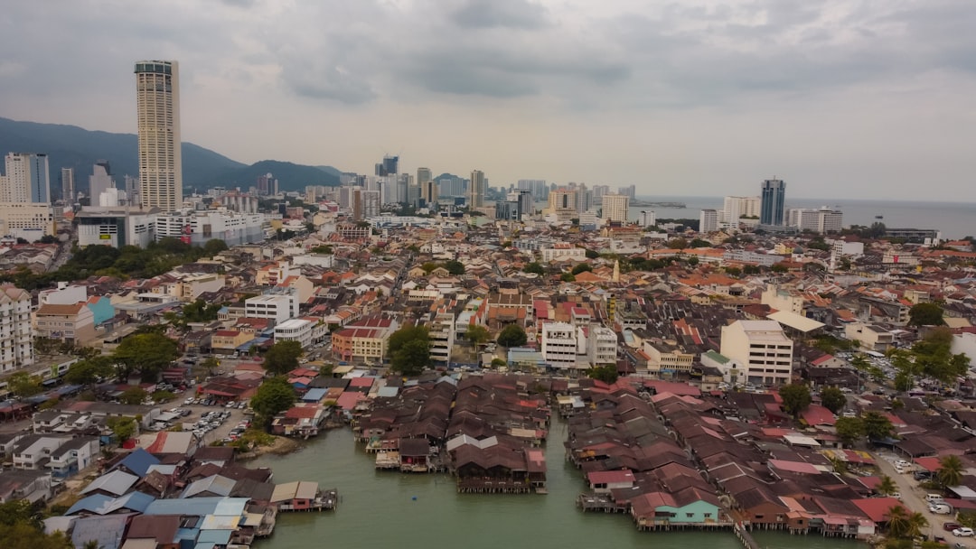 Aerial drone view of the Penang Heritage Clan Jetties at Weld Quay, showing stilt houses built over the water with the George Town skyline in the background