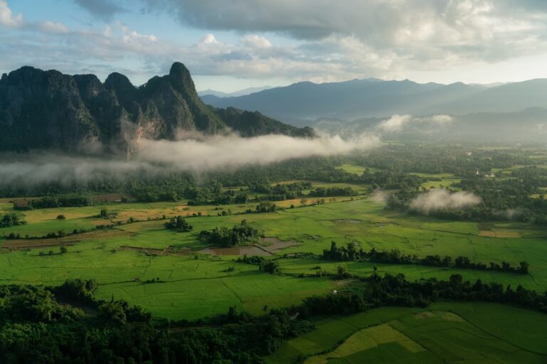 Misty karst limestone mountains and rice paddies surrounding Vang Vieng, Laos at dawn