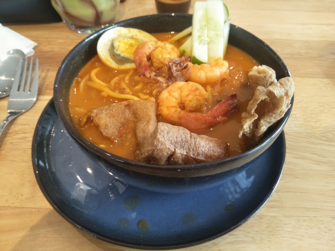 A bowl of Malaysian hawker noodle soup with prawns, egg, and cucumber, typical of the rich prawn-based noodle dishes found at George Town Penang hawker stalls