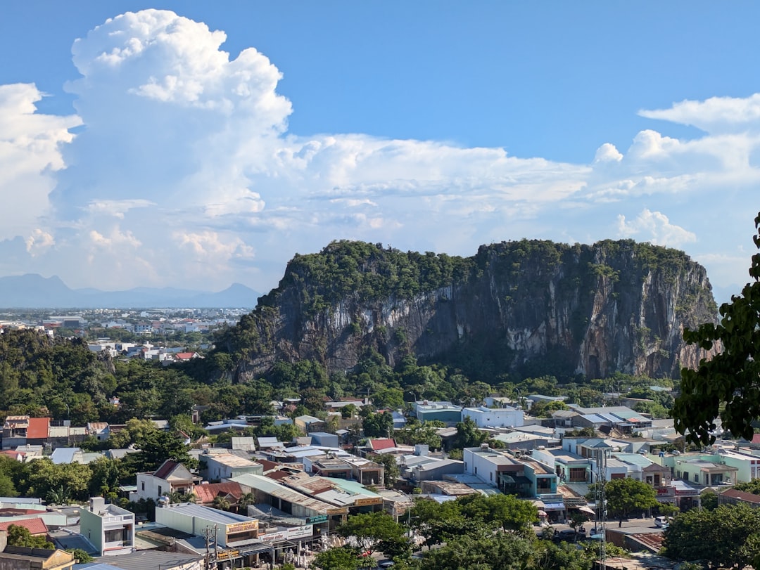 One of the Marble Mountains limestone peaks rising above the Da Nang neighbourhood below on a sunny day with dramatic clouds