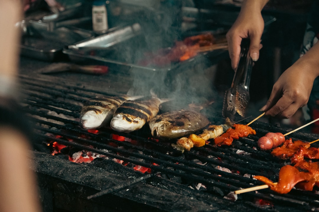 Grilled fish and seafood smoking over charcoal at an open-air BBQ market in the Philippines