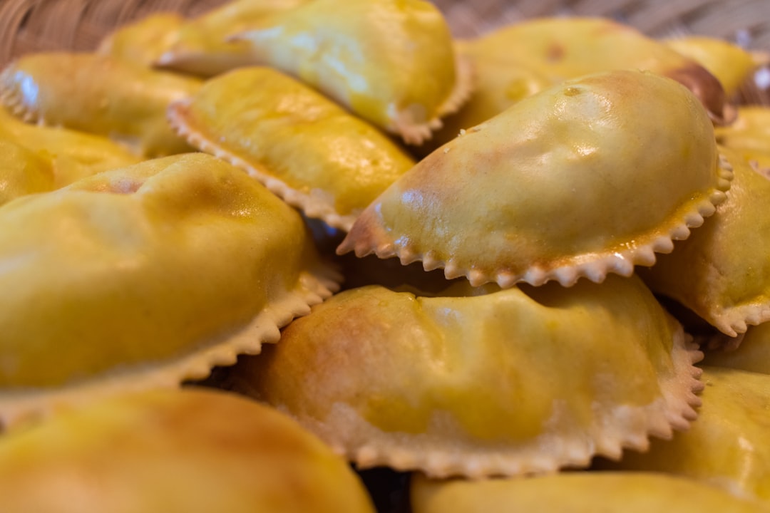 Golden deep-fried empanadas with crimped edges piled on a plate, similar to Vigan's iconic street empanada