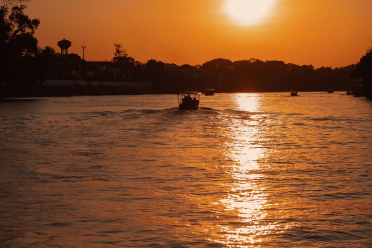Boats on a tropical river at golden sunset, evoking the slow riverside atmosphere of Kampot, Cambodia