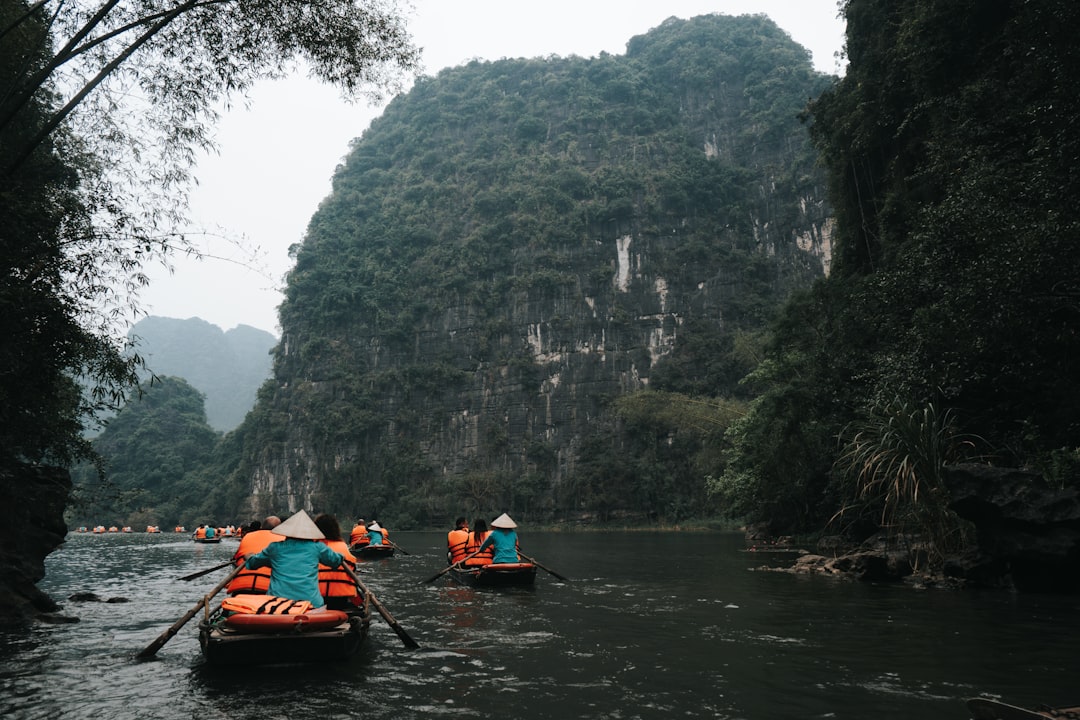 Boats paddling on a river flanked by tall limestone karst peaks in Southeast Asia